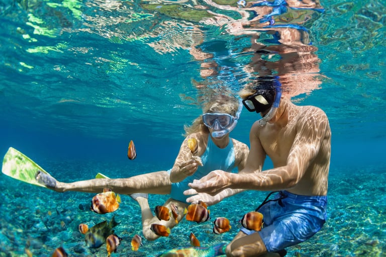 Couple snorkeling among tropical fish in crystal clear waters