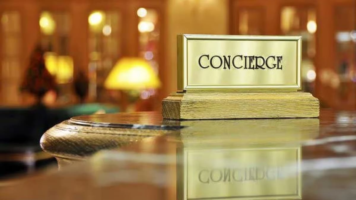 Concierge bell on marble counter with sign in luxury hotel lobby with warm lighting and blurred background